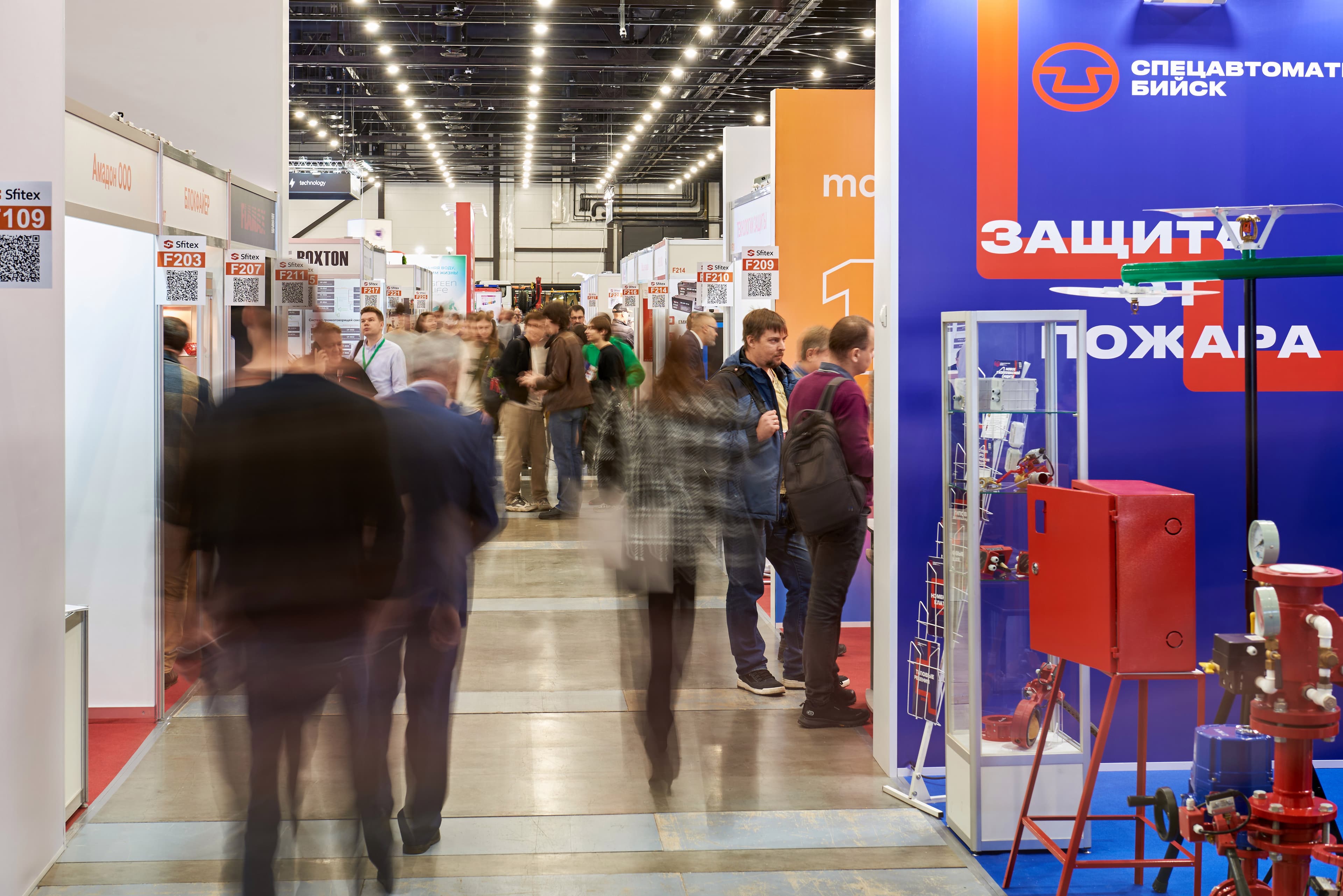 Visitors in the Sfitex exhibition aisle beside the Spetsavtomatika stand displaying fire suppression equipment.